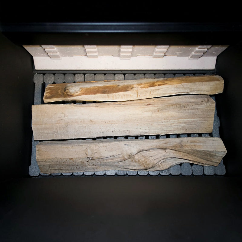 Blick in den Füllraum des GEMA Shop ROJEK PK BIO 25 Holzvergaserkessels mit drei eingelegten Scheitholzstücken.